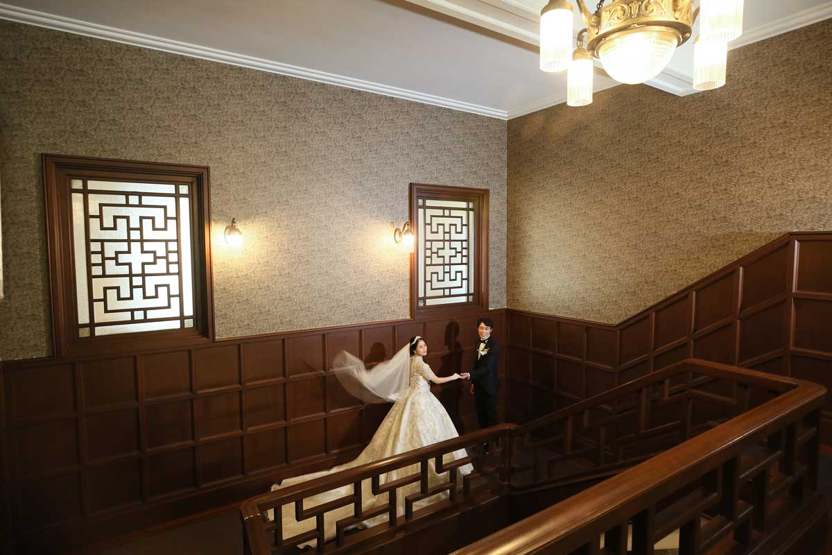 和洋折衷な階段で手を取り合う新郎新婦